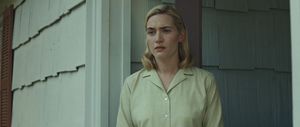Movie still from "Revolutionary Road" of Actor Kate Winslet being lit by soft lighting outside of a house. The lighting is meant to emulate sun around dusk.